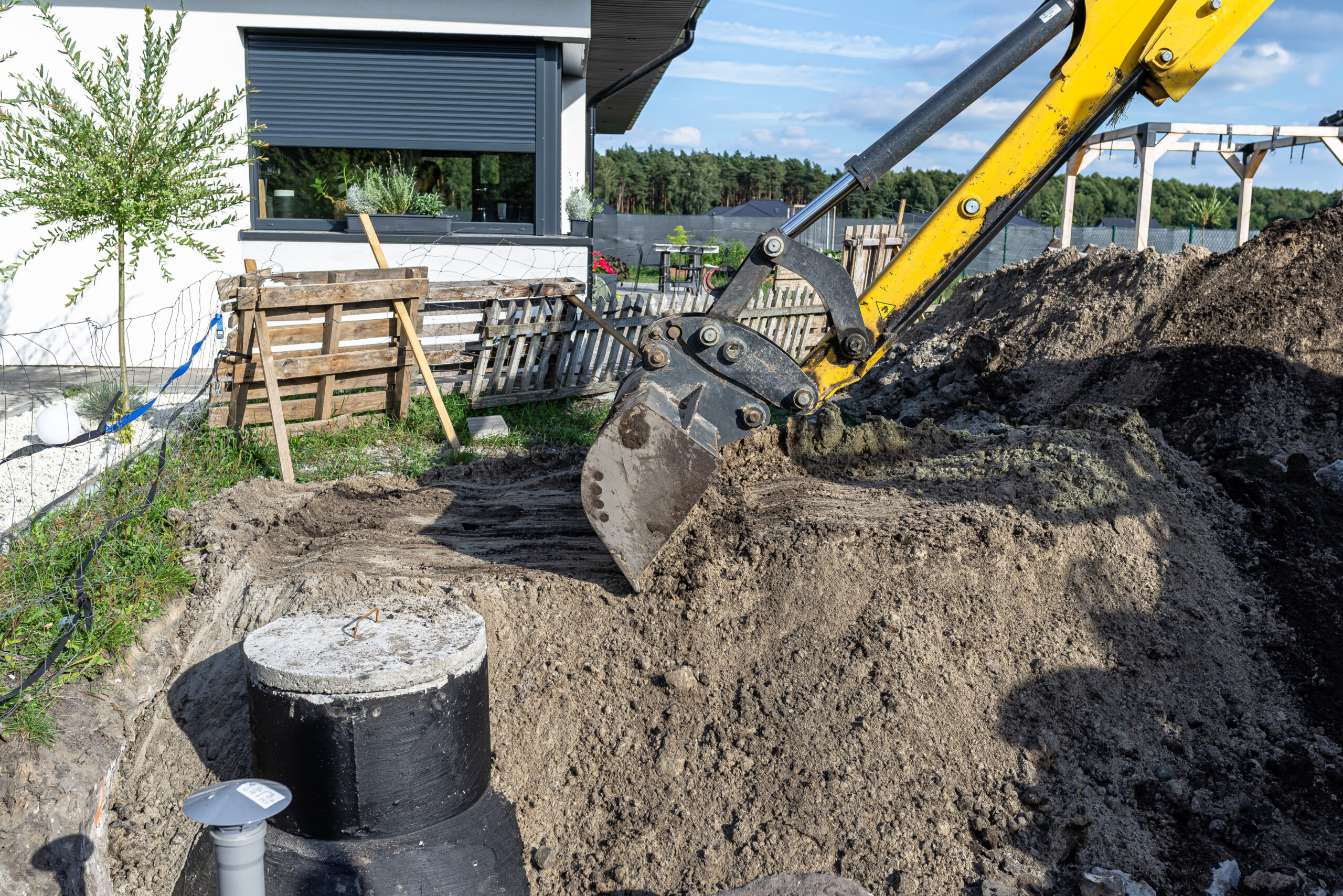 excavator burying a septic tank in low-lying residential area